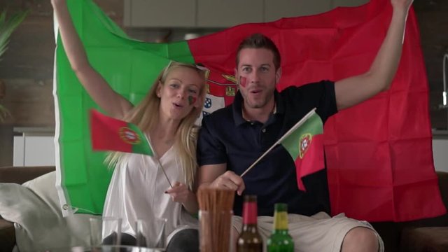 cheering portuguese fan couple with flag of portugal
