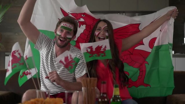 thrilled welsh soccer fan couple at home cheering for wales
