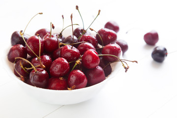 Ripe red cherries with water drops in bowl on a white background. Space for text