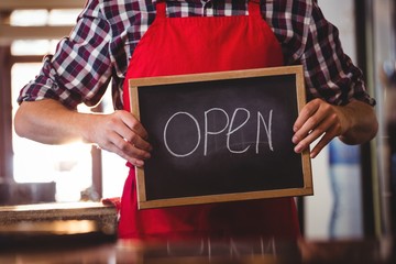 Mid section of waiter showing chalkboard with open sign