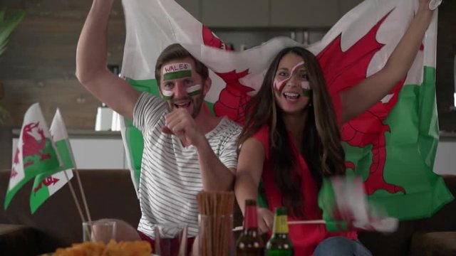 cheering overjoyed welsh fan couple holding flag of wales
