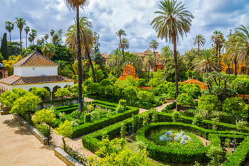 Obraz premium Romantyczny ogród publiczny pałacu w Sewilli w ciągu dnia. Tradycyjny średniowieczny wystrój wnętrza Pałacu Królewskiego w Andaluzji w Hiszpanii