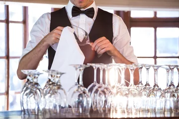 Tuinposter Mid section of bartender cleaning wineglass  © WavebreakMediaMicro