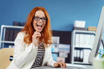 frau im büro schaut begeistert auf ihren pc