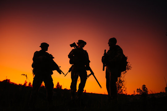 Silhouette of military soldiers with weapons at night. shot, hol