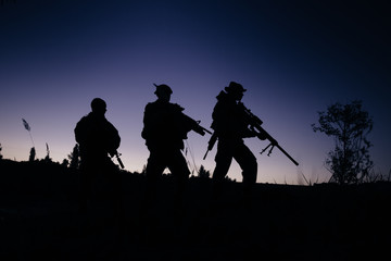 Fototapeta na wymiar Silhouette of military soldiers with weapons at night. shot, hol
