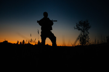 Fototapeta na wymiar Silhouette of military soldier or officer with weapons at night.