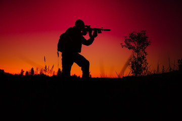 Silhouette of military soldier or officer with weapons at night.