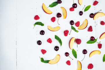 Various types of fruits with green leaves on white wood background