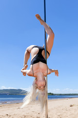 Naklejka premium blonde dancing on pole for summer on beach