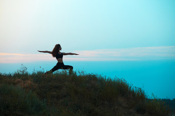 The silhouette of young woman is practicing yoga