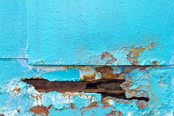 A hole in metal sheet iron blue. The edge of the hole spoiled by