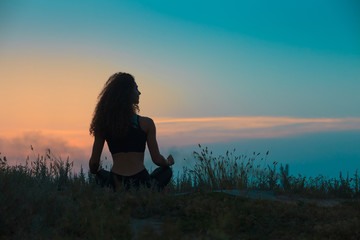 The silhouette of young woman is practicing yoga
