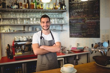 Fototapeta premium Portrait of confident barista with arms crossed at coffee house