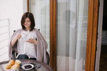 Young beautiful woman having breakfast on a cozy terrace