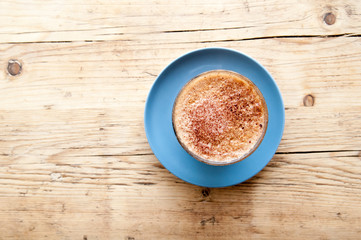 Fresh cup of coffee on a wooden table background in the cafe