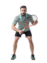 Concentrated tennis player bending and waiting for serve. Full body length portrait isolated over white studio background.