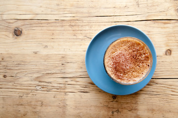 Fresh cup of coffee on a wooden table background in the cafe
