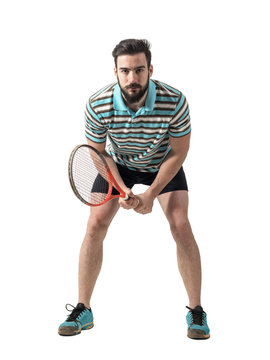 Focused young tennis player waiting to return serve holding racket with both hands. Full body length portrait isolated over white studio background.