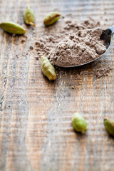 Scattered pods and spoon of powdered cardamom.