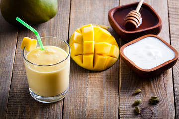 Glass of mango lassi, Indian drink made from yogurt with blended mango and honey, flavored with...
