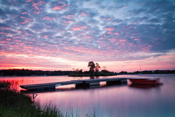 Naklejka na ściany i meble Lake landscape with beautiful sky and pier at sunrise photographed on long exposure.