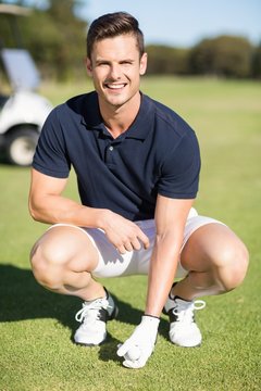 Portrait of man placing golf ball on tee 