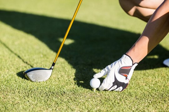 Cropped image of golfer placing golf ball on tee
