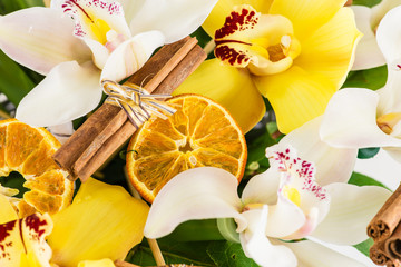 close-up of orange slice and cinnamon in a cymbidium orchid flow - obrazy, fototapety, plakaty