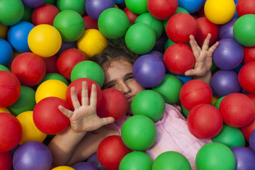 Girl having fun playing in a colorful plastic ball pool