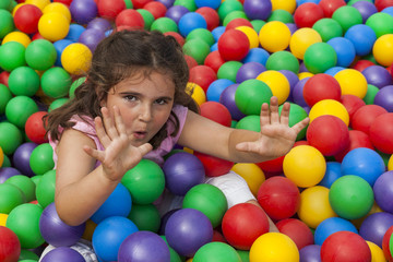 Fototapeta na wymiar Girl having fun playing in a colorful plastic ball pool
