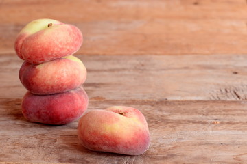 Fresh ripe flat peaches on the old wooden background. Useful sweet fruit dessert. Vegetarian food