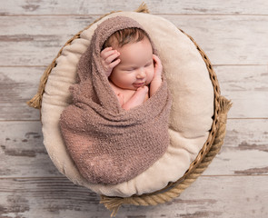 wrapped sleepy baby with folded legs and hands on head, top view