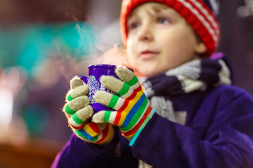 Little kid boy with hot chocolate on Christmas market
