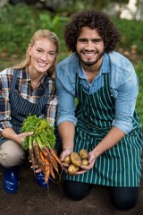 Gardeners holding harvested carrots and potatoes