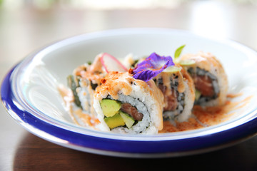 salmon tuna and avocado uramaki with spicy sauce in close up