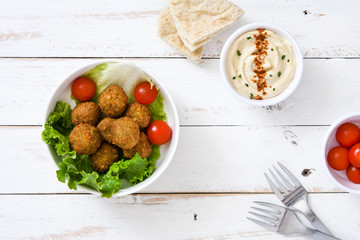 Vegetarian falafels and vegetables in bowl on a white wooden background

