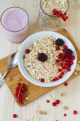 Porridge with berries and a cup of yogurt on a wooden table , a healthy breakfast