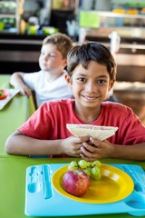 Happy boy with classmates having meal 