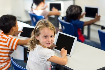 Fototapeta premium Schoolgirl with classmates using digital tablet