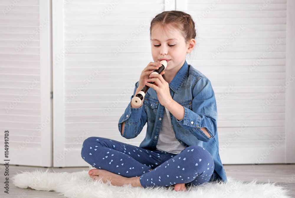 Poster Little girl playing flute on light background