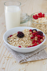 Oatmeal with berries and a glass of fresh milk on a wooden table, a healthy breakfast. Concept diet food.