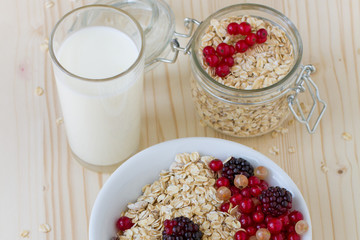 Oatmeal with berries and a glass of fresh milk on a wooden table, a healthy breakfast. Concept diet food.
