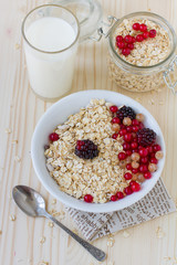 Oatmeal with berries and a glass of fresh milk on a wooden table, a healthy breakfast. Concept diet food.