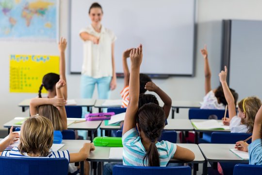 Teacher pointing students with raised hands