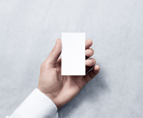 Hand holding blank vertical white business card design mockup. Clear calling card mock up template hold arm. Visiting pasteboard paper surface display front. Small pure offset card holder presentation