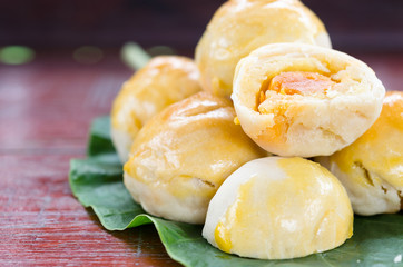 Chinese pastry cake made from flour, bean, egg and sugar on green leaf and wooden background