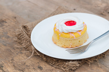 Butter cake with strawberry jam and whipped cream on wooden table