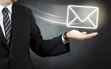 Geschäftsmann in Business Anzug hält Briefumschlag als Symbobild für Mail und E-Mail