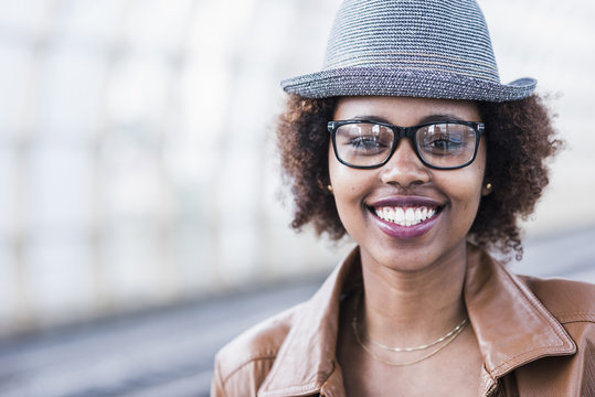 Portrait of smiling young woman wearing hat and glasses